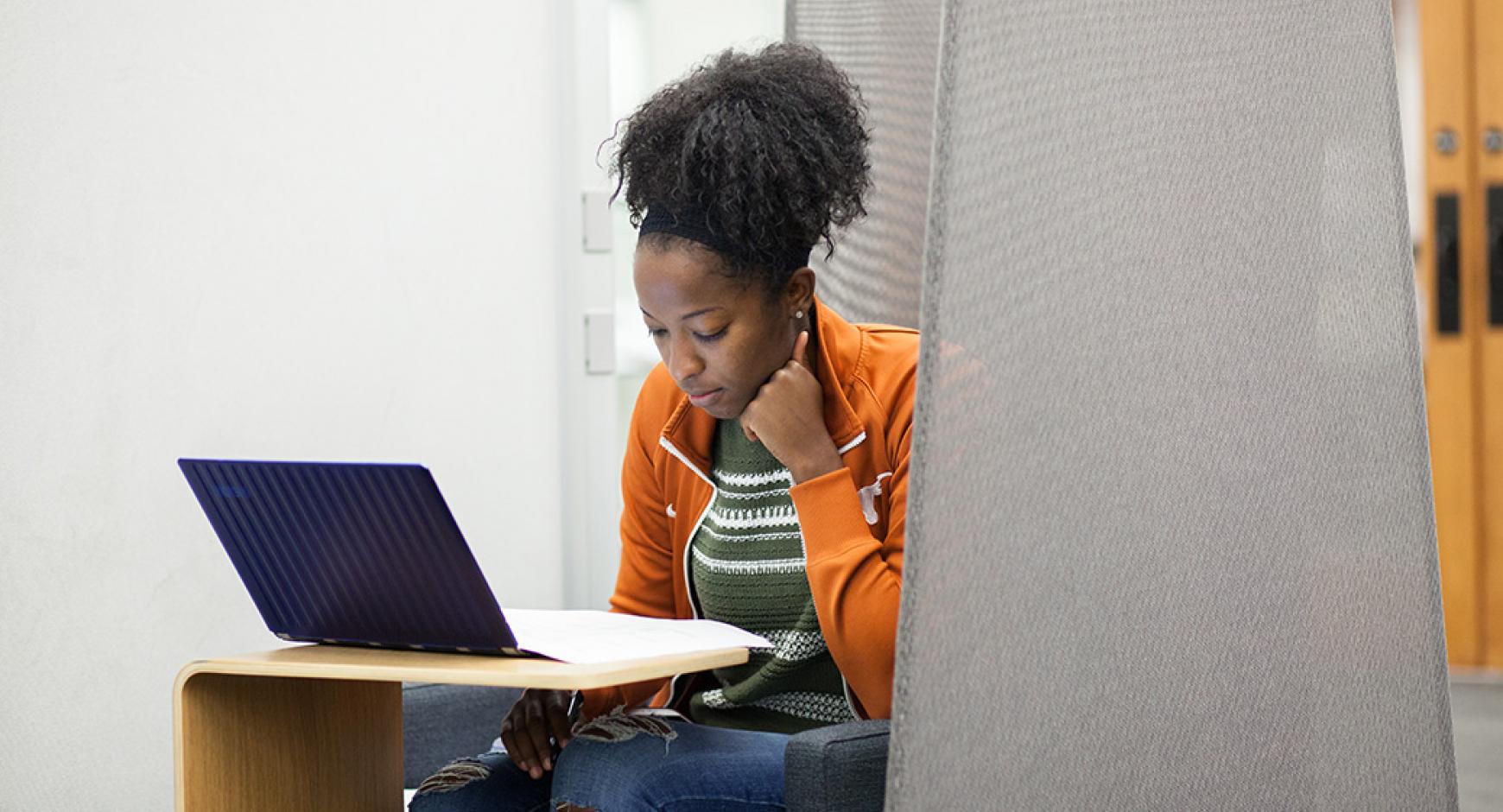 woman studying with laptop and documents in modern chair