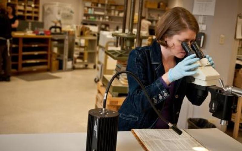 a person peering into a microscope in a book digitization lab